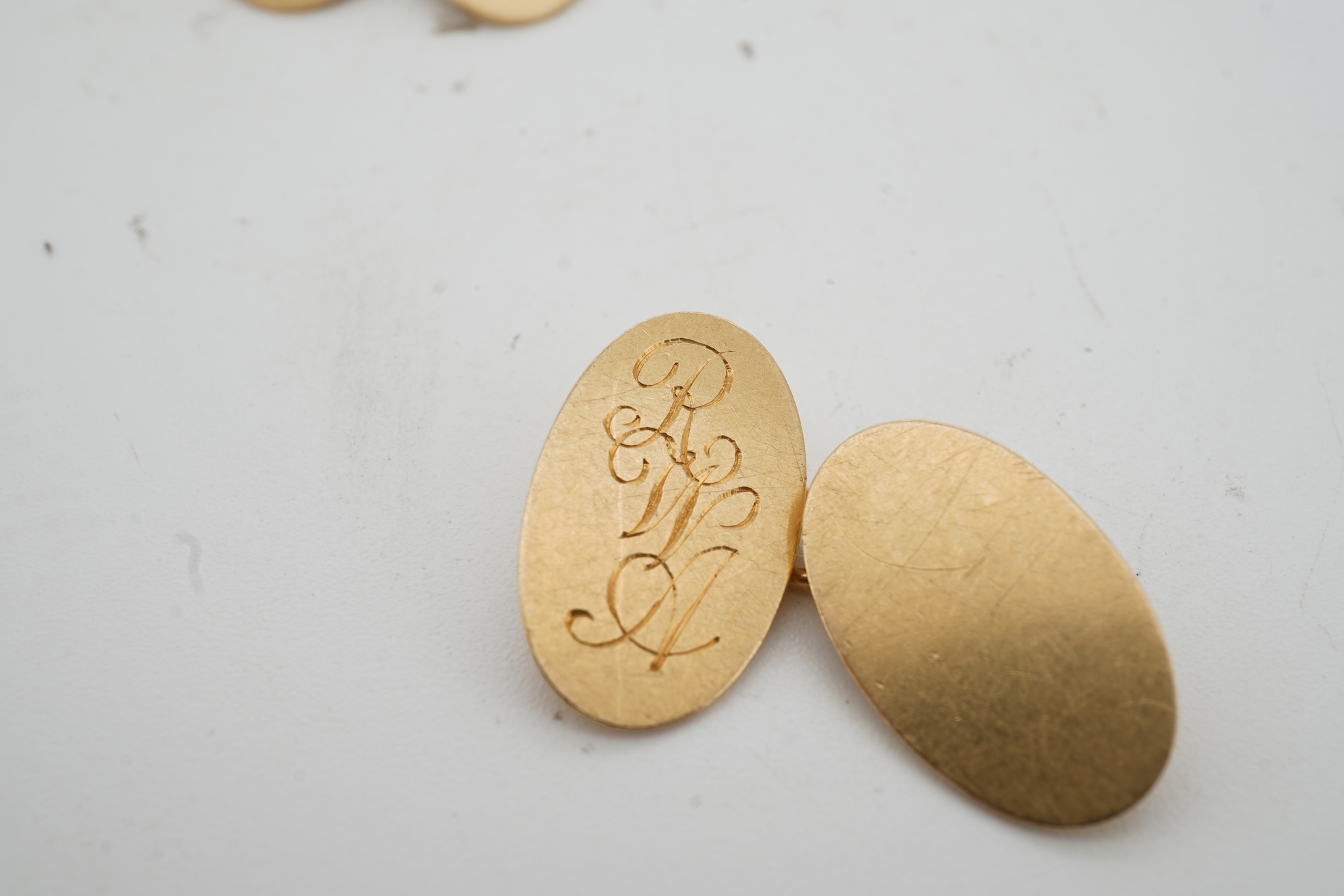 A pair of 18ct gold cufflinks, each end of oval outline, connected by chain linking, engraved with the initials RWA, length 1.8cm each, British hallmarks, combined gross weight approximately 7.5 grams